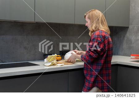 Woman slicing and arranging pomelo segments on plate in bright kitchen, food styling and plating for photography with natural light and minimalist props thoughtful composition, clean surfaces 140641825