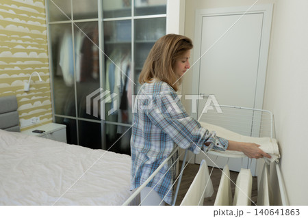 Female neatly arranges fabric items, Caucasian woman precisely coordinates drying clothes, Woman in bright environment systematically arranges and oversees drying of fabric and linen items Female neatly arranges fabric items, Caucasian woman precisely coordinates drying clothes, Woman in bright environment systematically arranges and oversees drying of fabric and linen items 140641863