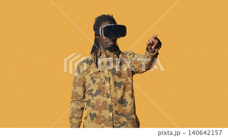 Cool man using virtual reality glasses in studio, enjoying 3d vision and interactive simulation vr headset on camera, with modern person having fun with goggles, artificial intelligence concept. Cool man using virtual reality glasses in studio, enjoying 3d vision and interactive simulation vr headset on camera, with modern person having fun with goggles, artificial intelligence concept. 140642157