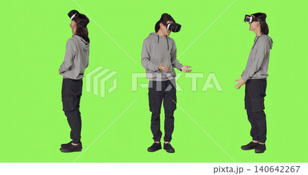 Young man uses virtual reality tech on camera with full body green screen template, using interactive 3d vision on vr glasses, with modern person having fun with artificial intelligence headset. 140642267