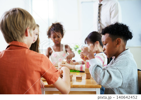 Excited black schoolgirl playing with wooden blocks in classroom 140642452