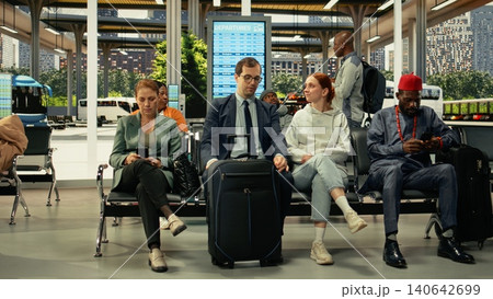 Young couple waiting in crowded bus terminal before long-haul interstate journey. Man and woman with luggage and carry-on bags check departure board screen, affordable overnight coach travel. Young couple waiting in crowded bus terminal before long-haul interstate journey. Man and woman with luggage and carry-on bags check departure board screen, affordable overnight coach travel. 140642699