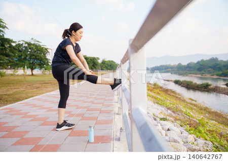 Woman stretching leg on bridge after or before outdoor workout Woman stretching leg on bridge after or before outdoor workout 140642767