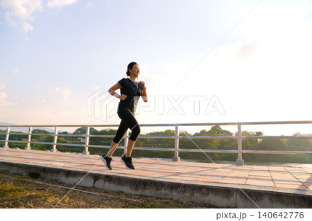 Woman jogging outdoors on bridge during morning exercise Woman jogging outdoors on bridge during morning exercise 140642776