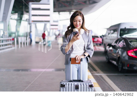 Asian woman traveler using smartphone with luggage at airport terminal Asian woman traveler using smartphone with luggage at airport terminal 140642902
