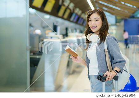 Asian woman traveler with suitcase using smartphone at airport check-in Asian woman traveler with suitcase using smartphone at airport check-in 140642904