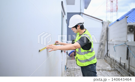 Asian Construction Engineer Inspector Measuring Wall with Tape Measure at Building Site Asian Construction Engineer Inspector Measuring Wall with Tape Measure at Building Site 140643464