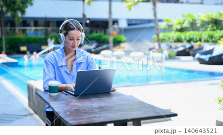Professional businesswoman working on laptop by the hotel pool during vacation, representing remote work, digital nomad lifestyle Professional businesswoman working on laptop by the hotel pool during vacation, representing remote work, digital nomad lifestyle 140643521