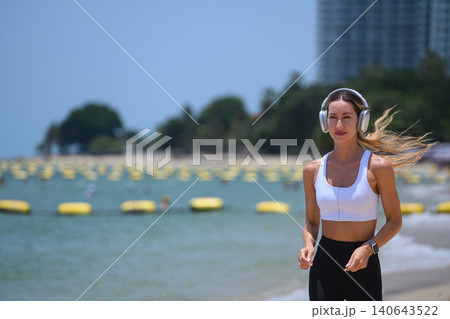 Beautiful female athlete in white sports bra exercising on the sunny beach 140643522
