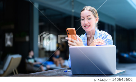 Cheerful digital nomad woman having a video call or seeing good news on phone Cheerful digital nomad woman having a video call or seeing good news on phone 140643606