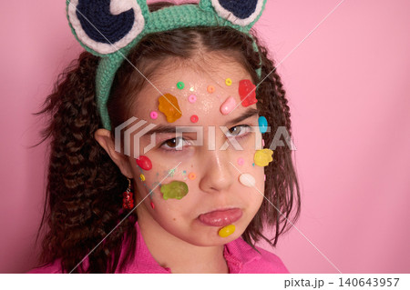 Whimsical Portrait of a Girl with Candy and Surprised Expression Against a Pink Background Whimsical Portrait of a Girl with Candy and Surprised Expression Against a Pink Background 140643957