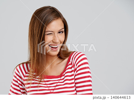 Wink, portrait and girl in studio with smile for fun mood, positive attitude and mockup space. Playful, cute and happy gen z woman on white background for wellness, relax and flirt with emoji face 140644613