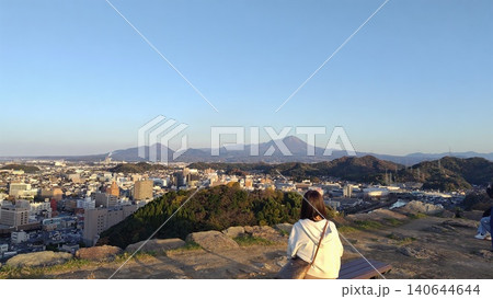 米子城跡の天守台から大山と市街地の絶景を眺める観光客の女性の後ろ姿 140644644