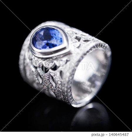 Gemstone, silver and ring on a black background of luxury or expensive present for engagement or marriage in studio. Jewelry, diamonds and blue or sapphire rock in closeup, reflection and accessory 140645487