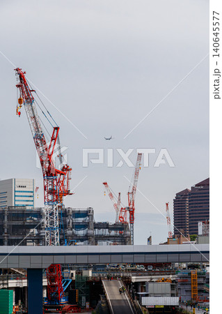 高輪ゲートウェイ駅前の建設クレーンと上空の旅客機 高輪ゲートウェイ駅前の建設クレーンと上空の旅客機 140645577