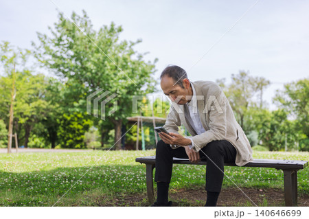 公園のベンチでスマートフォンを見る日本人男性 公園のベンチでスマートフォンを見る日本人男性 140646699