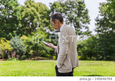 公園でスマートフォンを見る日本人シニアの男性 公園でスマートフォンを見る日本人シニアの男性 140646769