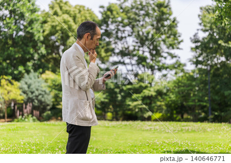 公園でスマートフォンを見る日本人シニアの男性 公園でスマートフォンを見る日本人シニアの男性 140646771