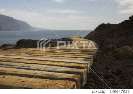 Wooden path curving along volcanic coast to ocean Wooden path curving along volcanic coast to ocean 140647025