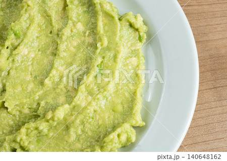 Fresh homemade guacamole sauce served on a white ceramic plate, top view copy space. Fresh homemade guacamole sauce served on a white ceramic plate, top view copy space. 140648162