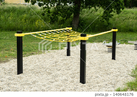Rope climbing net obstacle at an outdoor fitness playground. Calisthenics workout park equipment Rope climbing net obstacle at an outdoor fitness playground. Calisthenics workout park equipment 140648176
