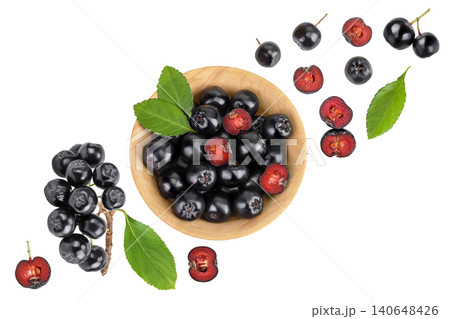 Chokeberry with leaf in a wooden bowl isolated on white background. Black aronia. Top view. Flat lay Chokeberry with leaf in a wooden bowl isolated on white background. Black aronia. Top view. Flat lay 140648426
