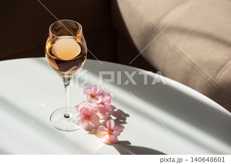 Rose wine glass on white table with pink flowers 140648601