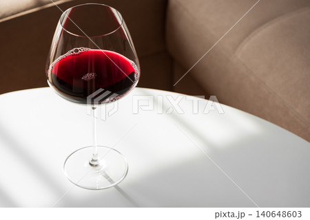 Red wine glass sitting on white table Red wine glass sitting on white table 140648603