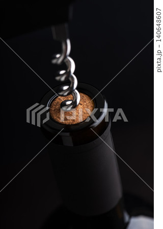 Corkscrew opening a wine bottle with dark background Corkscrew opening a wine bottle with dark background 140648607