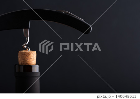 Corkscrew opening wine bottle with a cork on a dark background Corkscrew opening wine bottle with a cork on a dark background 140648613
