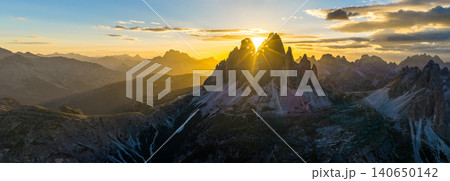 Panoramic view of Tre Cime di Lavaredo glowing in golden sunset light in the Italian Dolomites. Dramatic alpine landscape with rugged peaks, winding trails and breathtaking scenery. Panoramic view of Tre Cime di Lavaredo glowing in golden sunset light in the Italian Dolomites. Dramatic alpine landscape with rugged peaks, winding trails and breathtaking scenery. 140650142