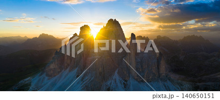 Spectacular sunset over Tre Cime di Lavaredo in the Italian Dolomites. Golden sunburst shines between iconic limestone peaks, creating a dramatic alpine mountain landscape. Spectacular sunset over Tre Cime di Lavaredo in the Italian Dolomites. Golden sunburst shines between iconic limestone peaks, creating a dramatic alpine mountain landscape. 140650151
