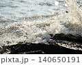 陽光の中で岩場に砕ける波しぶき 140650191