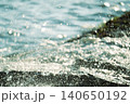 陽光の中で岩場に砕ける波しぶき 140650192