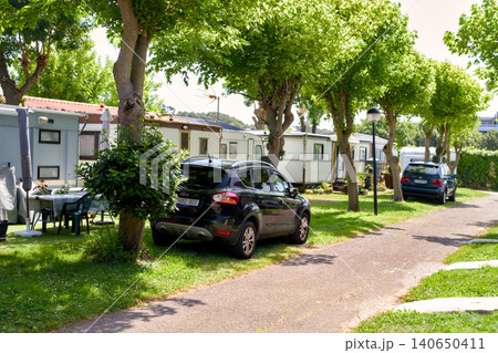 Tree-Lined Campsite Road With Cars and Static Caravans on Both Sides Tree-Lined Campsite Road With Cars and Static Caravans on Both Sides 140650411