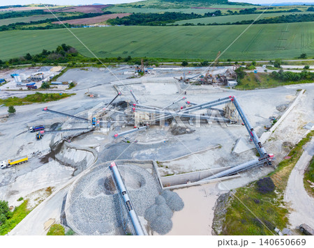 Mining complex with extensive conveyors and settling ponds visible. Expansive gravel processing facility equipped with multiple transport belts and water treatment units 140650669