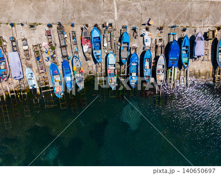 Vivid harbor vessels. Fishing crafts arranged along tranquil harbor. Brightly colored boats anchored at harbor with reflections creating picturesque maritime scenery Vivid harbor vessels. Fishing crafts arranged along tranquil harbor. Brightly colored boats anchored at harbor with reflections creating picturesque maritime scenery 140650697