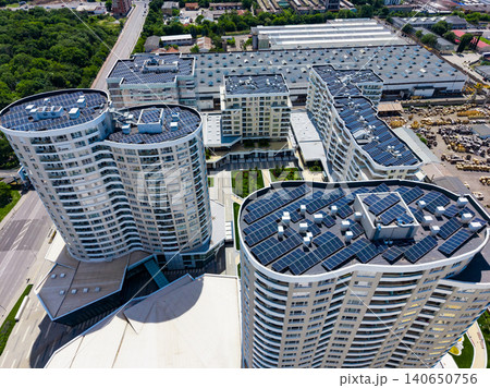 Construction of modern buildings with solar panels located in a city with green spaces around them in daylight Construction of modern buildings with solar panels located in a city with green spaces around them in daylight 140650756