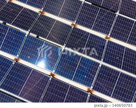 Solar panels are arranged in rows on a rooftop under sunlight during the day in a residential area, showing signs of wear and dust accumulation Solar panels are arranged in rows on a rooftop under sunlight during the day in a residential area, showing signs of wear and dust accumulation 140650783