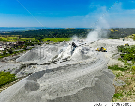 Granite quarry site with machines and piles of stone dust during a sunny day in an outdoor location 140650800