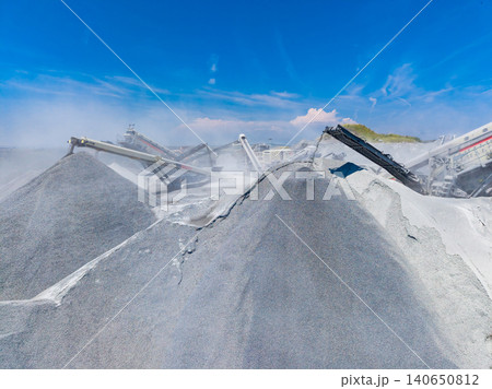 Granite quarry workers carry out operations to process stone in a busy work site under clear blue skies during the day Granite quarry workers carry out operations to process stone in a busy work site under clear blue skies during the day 140650812