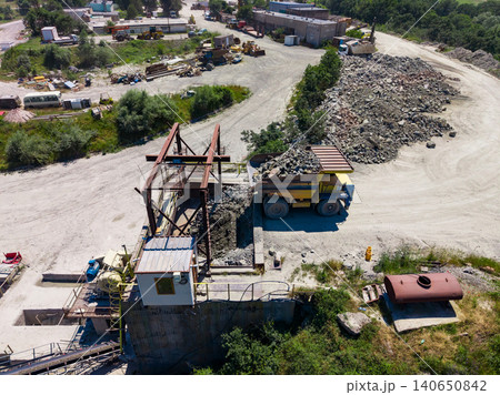 Granite quarry site with heavy machinery processing stone materials during daytime operations Granite quarry site with heavy machinery processing stone materials during daytime operations 140650842