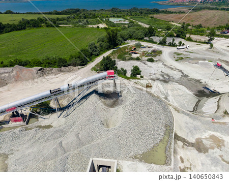 Granite quarry scene showing large machinery, rocky terrain, and green land near water on a clear day with workers present Granite quarry scene showing large machinery, rocky terrain, and green land near water on a clear day with workers present 140650843