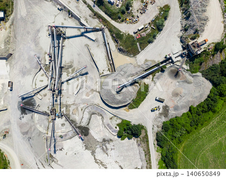 Granite quarry site with processing equipment and stockpiles during daytime in an industrial setting Granite quarry site with processing equipment and stockpiles during daytime in an industrial setting 140650849