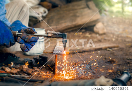 Cutting steel with gas, gas welding and oxy-fuel cutting are processes that use fuel gases and oxygen to weld and cut metals, respectively. industrial worker cutting thick steel in workshop. 140650891