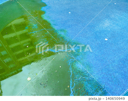 Pool water shows signs of algae growth and dirt in a residential area, indicating a need for cleaning and maintenance during the summer season Pool water shows signs of algae growth and dirt in a residential area, indicating a need for cleaning and maintenance during the summer season 140650949