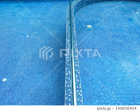 Water surface of a swimming pool with tiles showing blue colors and a clear dividing line in the middle Water surface of a swimming pool with tiles showing blue colors and a clear dividing line in the middle 140650954