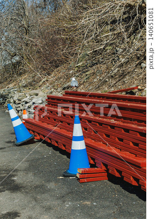 Construction materials and traffic cones are arranged along a gravel path in an outdoor area during the day Construction materials and traffic cones are arranged along a gravel path in an outdoor area during the day 140651081