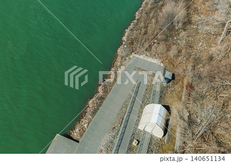 Dock area along a green river with a small shelter and rocky shore during a sunny day in early spring Dock area along a green river with a small shelter and rocky shore during a sunny day in early spring 140651134