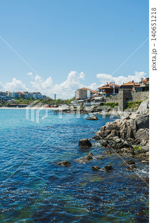 Village by water with cheerful surroundings. Sundrenched coastal hamlet with shimmering surfaces and peaceful breezes creating perfect vacation ambiance for travelers 140651218